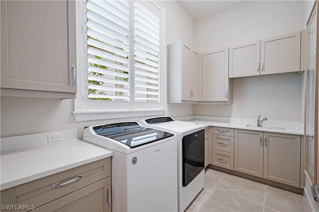 washroom with cabinets, light tile patterned floors, washing machine and clothes dryer, and sink