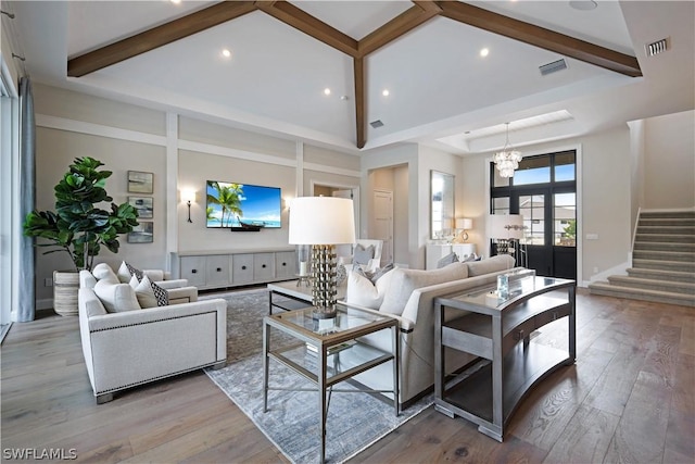 living room featuring a towering ceiling, a chandelier, and light hardwood / wood-style flooring