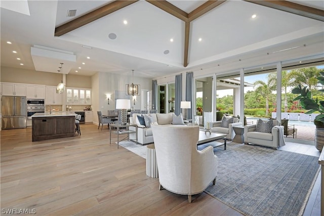 living room featuring beamed ceiling, an inviting chandelier, light hardwood / wood-style floors, sink, and high vaulted ceiling