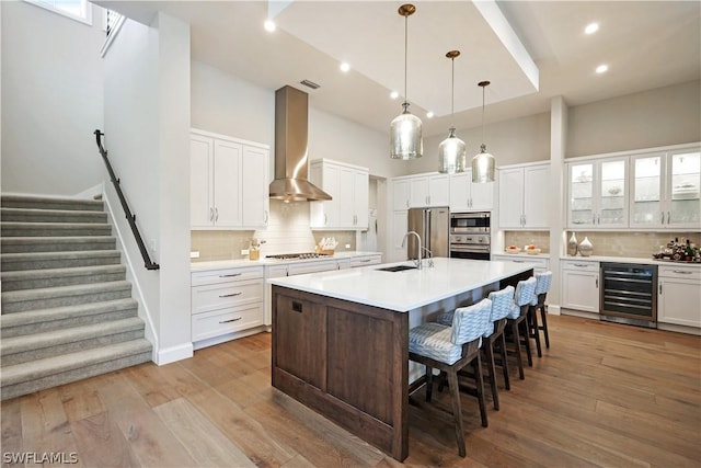 kitchen featuring appliances with stainless steel finishes, white cabinetry, wall chimney exhaust hood, and sink