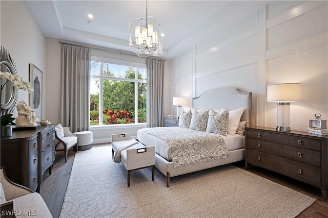 bedroom featuring an inviting chandelier, dark hardwood / wood-style floors, and a tray ceiling