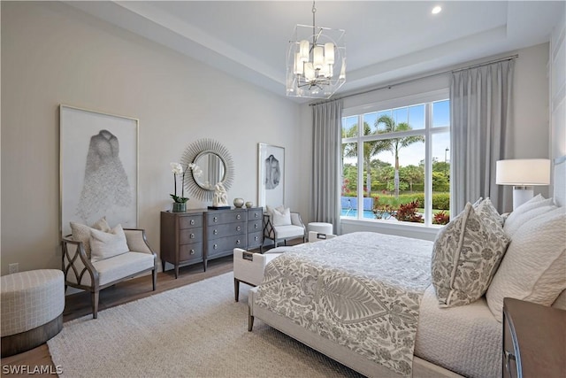 bedroom with hardwood / wood-style floors, a raised ceiling, and an inviting chandelier