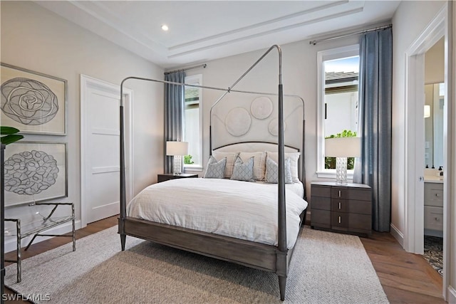 bedroom with ensuite bathroom and light hardwood / wood-style flooring