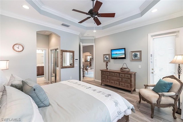 bedroom with ceiling fan, ensuite bathroom, crown molding, and a tray ceiling