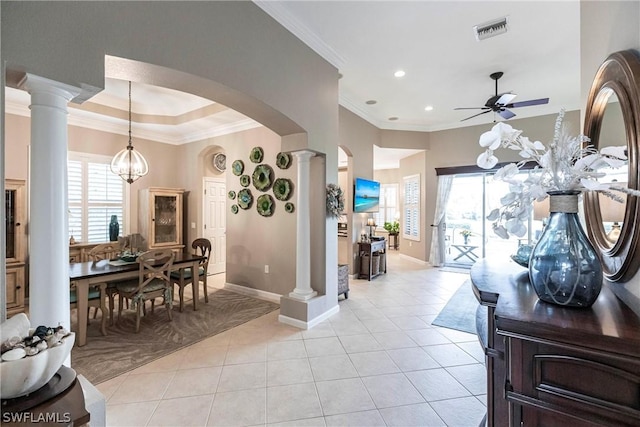 tiled entrance foyer featuring ceiling fan with notable chandelier, decorative columns, ornamental molding, and a healthy amount of sunlight