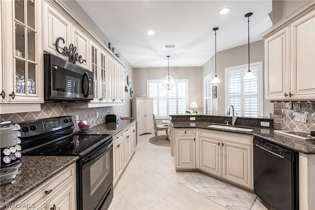 kitchen featuring decorative light fixtures, a notable chandelier, black appliances, dark stone countertops, and sink