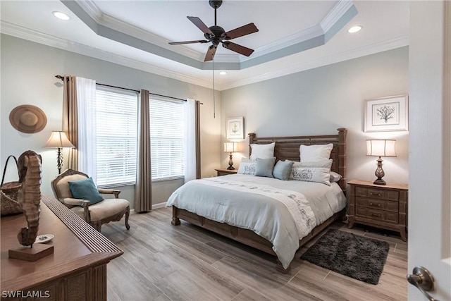 bedroom featuring multiple windows, ceiling fan, a tray ceiling, and ornamental molding