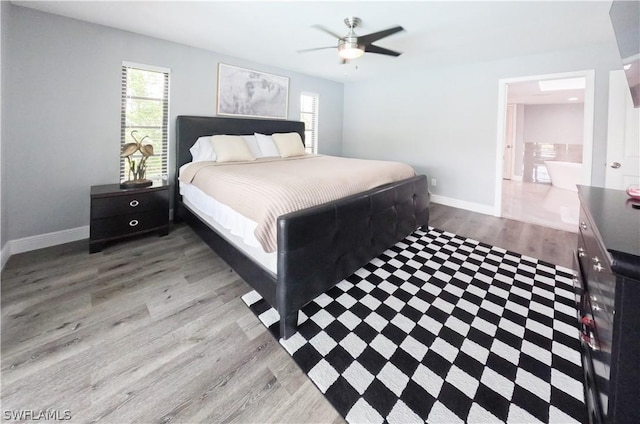 bedroom with hardwood / wood-style floors, ceiling fan, and connected bathroom