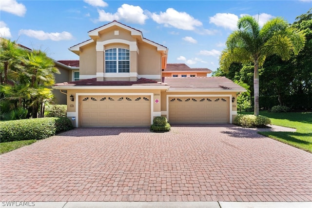 mediterranean / spanish home with a tile roof, decorative driveway, and stucco siding