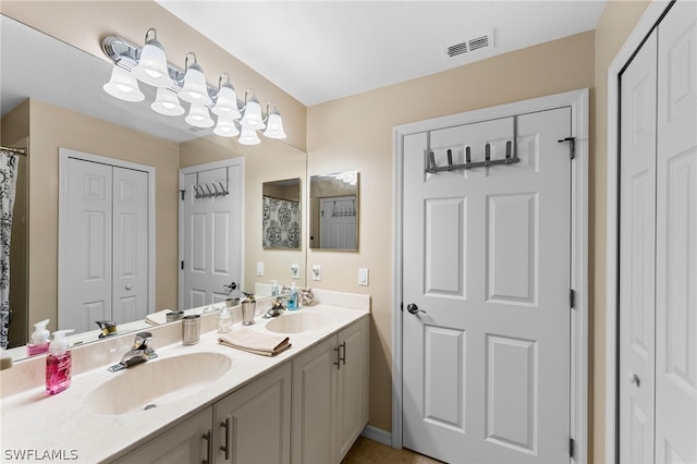 bathroom with a closet, visible vents, double vanity, and a sink