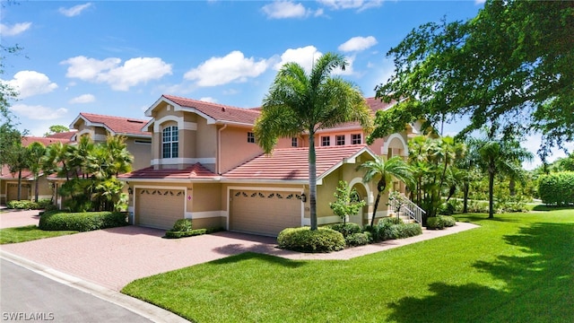 mediterranean / spanish-style house with stucco siding, decorative driveway, a front yard, and a tile roof