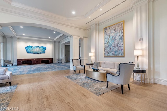 living room featuring decorative columns, crown molding, and light wood-type flooring