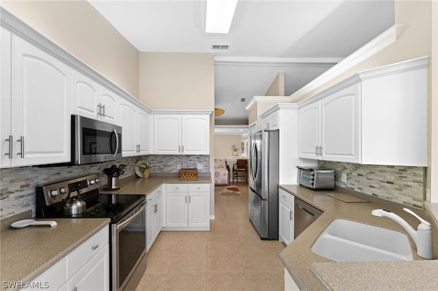 kitchen with light tile patterned floors, appliances with stainless steel finishes, white cabinetry, and a sink