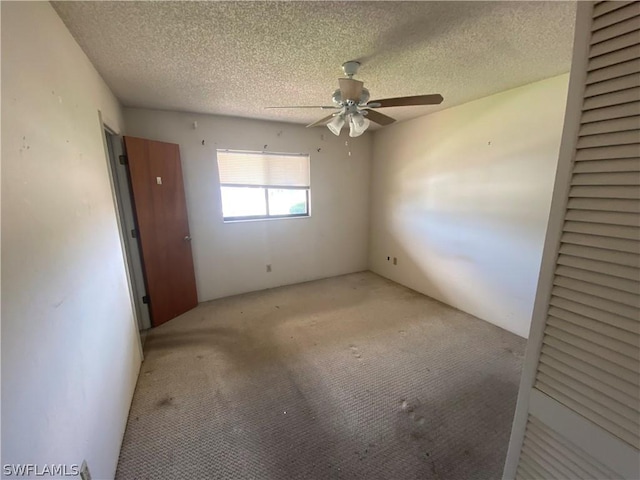 empty room featuring ceiling fan, light carpet, and a textured ceiling