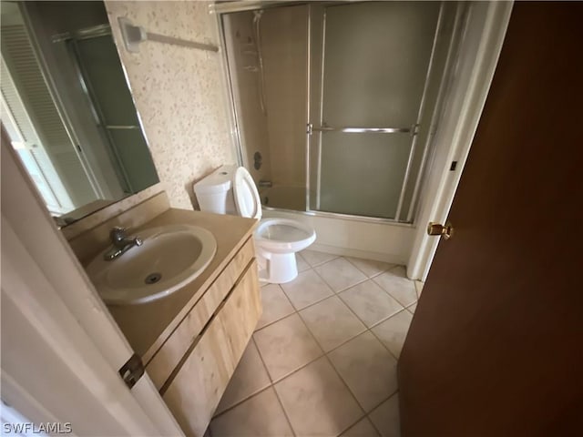 full bathroom with tile patterned flooring, enclosed tub / shower combo, vanity, and toilet