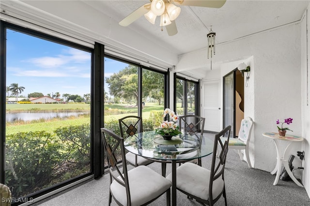 sunroom with ceiling fan and a water view