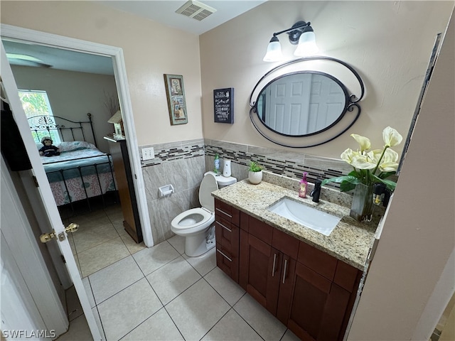 bathroom with tile patterned flooring, tasteful backsplash, toilet, vanity, and tile walls