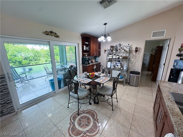 dining area with a notable chandelier, lofted ceiling, and light tile patterned floors