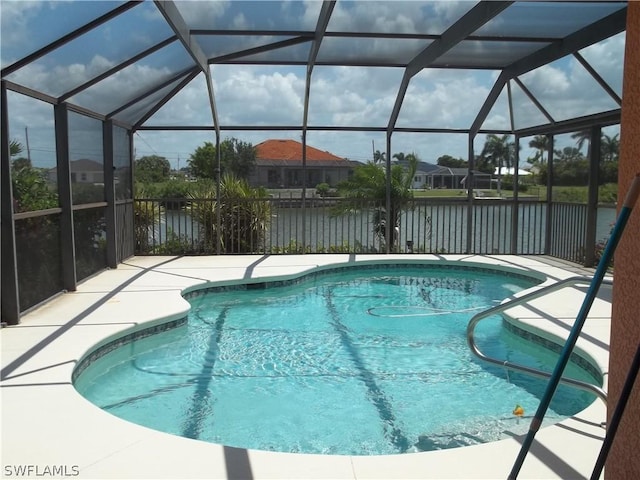 view of pool featuring a patio, glass enclosure, and a water view