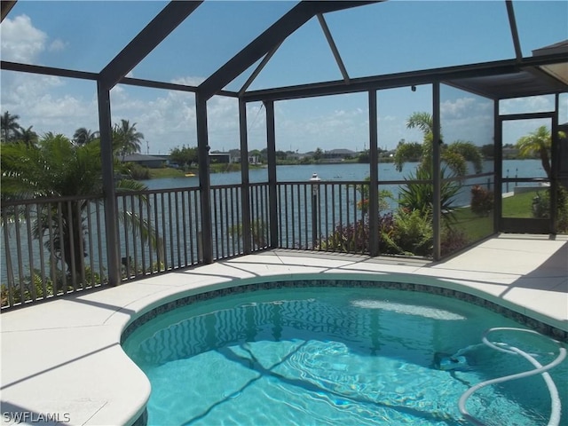 view of pool with a patio, glass enclosure, and a water view