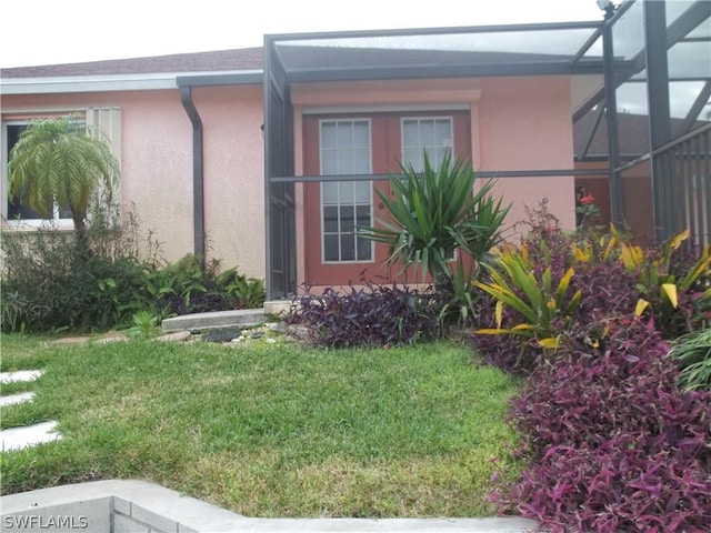 view of side of home with glass enclosure and a lawn