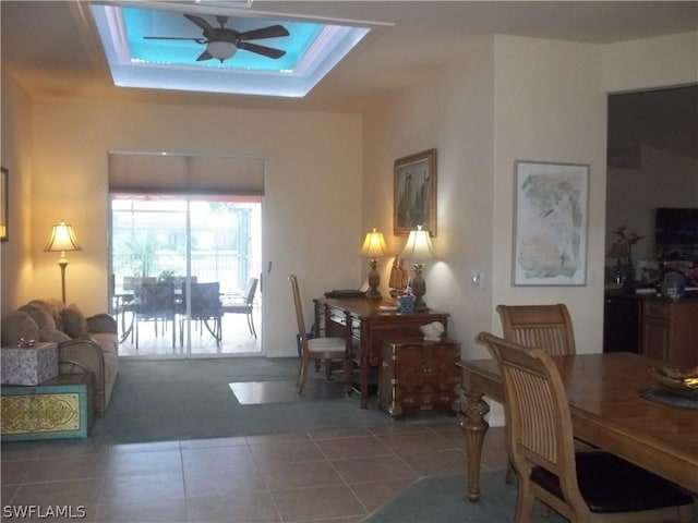 dining room featuring ceiling fan, a raised ceiling, and tile patterned flooring