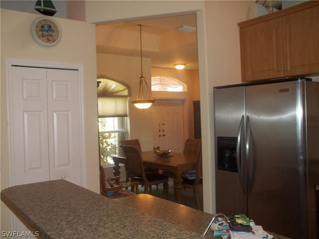 kitchen with stainless steel refrigerator with ice dispenser and decorative light fixtures