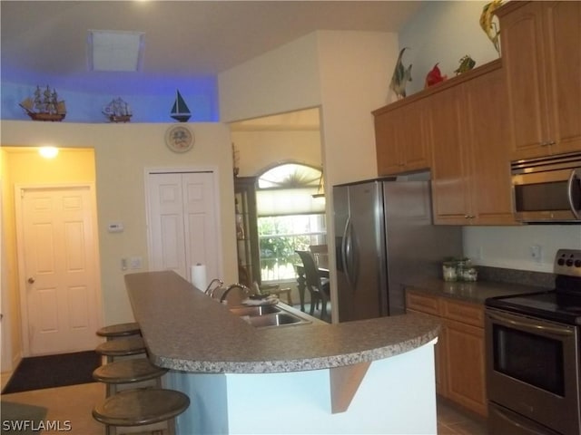 kitchen featuring sink, a kitchen bar, an island with sink, and appliances with stainless steel finishes