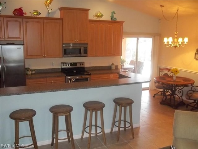 kitchen featuring appliances with stainless steel finishes, a kitchen bar, decorative light fixtures, and a notable chandelier