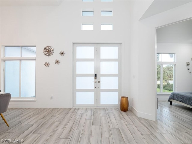 entrance foyer featuring french doors, a high ceiling, and light wood-type flooring