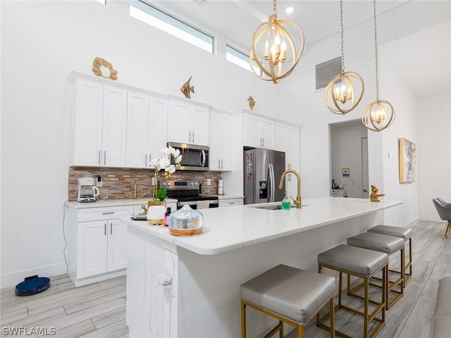 kitchen with white cabinetry, an island with sink, a chandelier, and appliances with stainless steel finishes