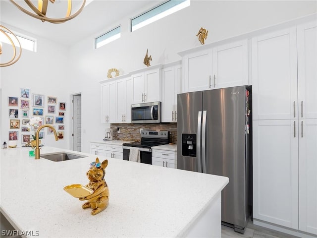 kitchen featuring decorative backsplash, light stone counters, stainless steel appliances, sink, and white cabinetry