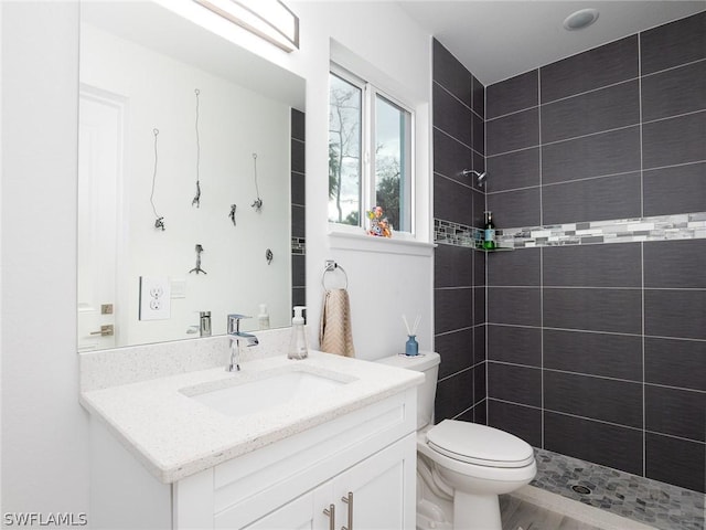 bathroom with vanity, toilet, and tiled shower