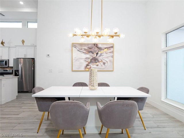 dining space with light hardwood / wood-style floors and an inviting chandelier