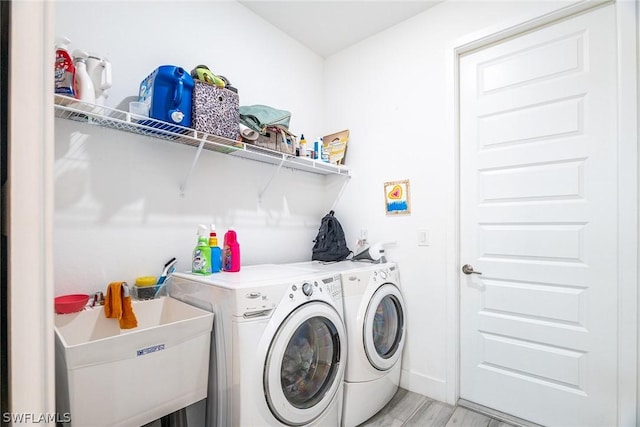 clothes washing area featuring light hardwood / wood-style floors, separate washer and dryer, and sink