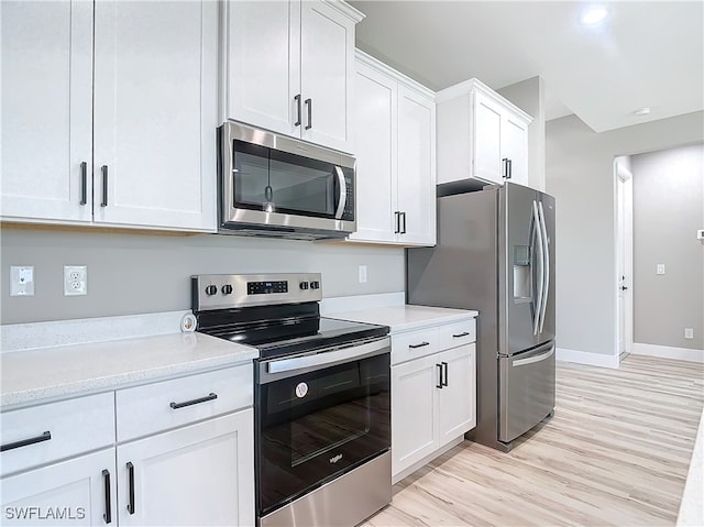 kitchen with white cabinets, appliances with stainless steel finishes, and light wood-type flooring