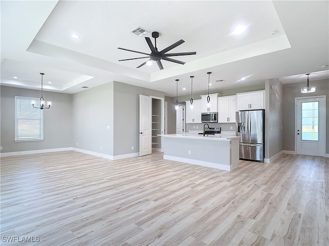 kitchen featuring ceiling fan with notable chandelier, appliances with stainless steel finishes, plenty of natural light, and a raised ceiling