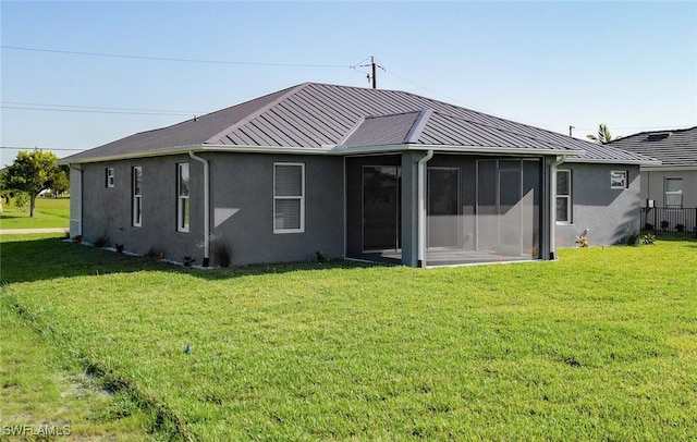 rear view of house featuring a sunroom and a yard