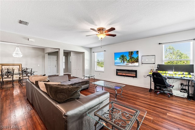 living room with dark hardwood / wood-style flooring, ceiling fan, and a textured ceiling