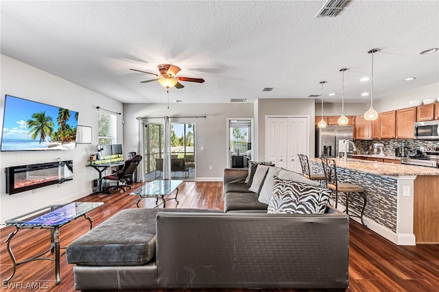 living room with ceiling fan, sink, a textured ceiling, and dark hardwood / wood-style floors