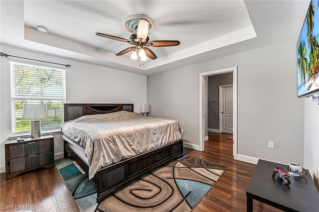 bedroom featuring dark hardwood / wood-style flooring, a raised ceiling, and ceiling fan