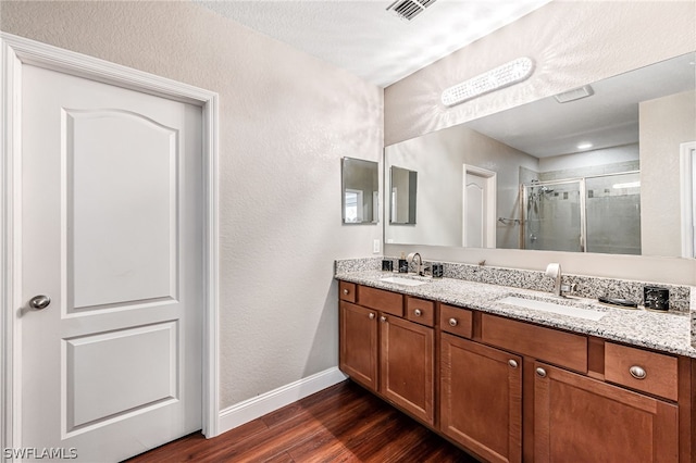 bathroom featuring wood-type flooring, vanity, and a shower with shower door