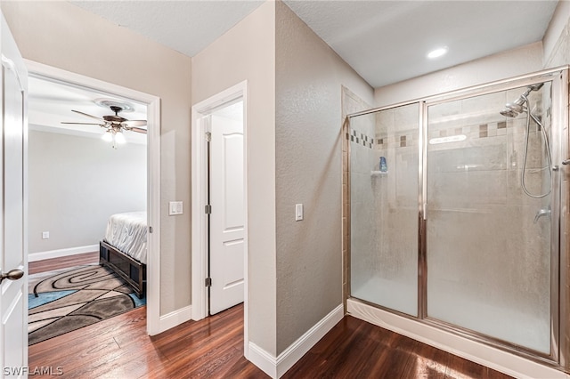 bathroom featuring wood-type flooring, a shower with door, and ceiling fan