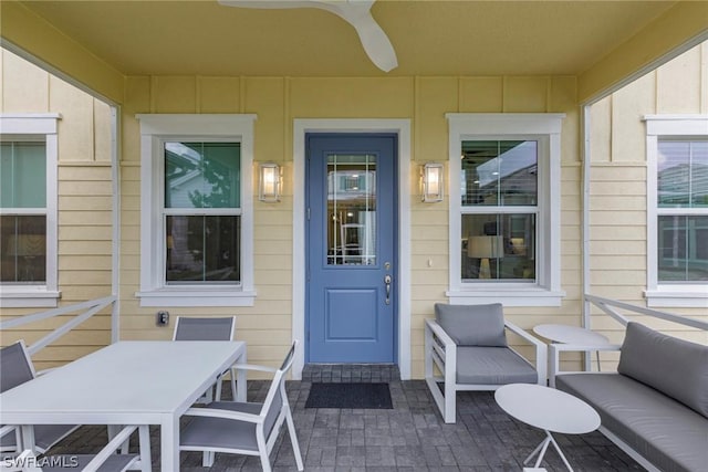 view of exterior entry with ceiling fan and a patio