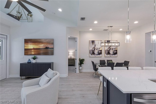 interior space with pendant lighting, ceiling fan, a kitchen bar, and light hardwood / wood-style flooring