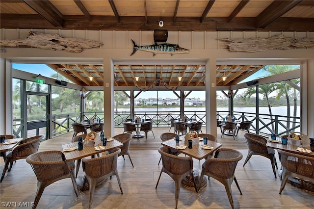 dining room with vaulted ceiling with beams and a water view