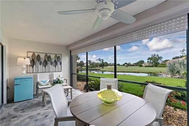 sunroom / solarium with a water view and ceiling fan