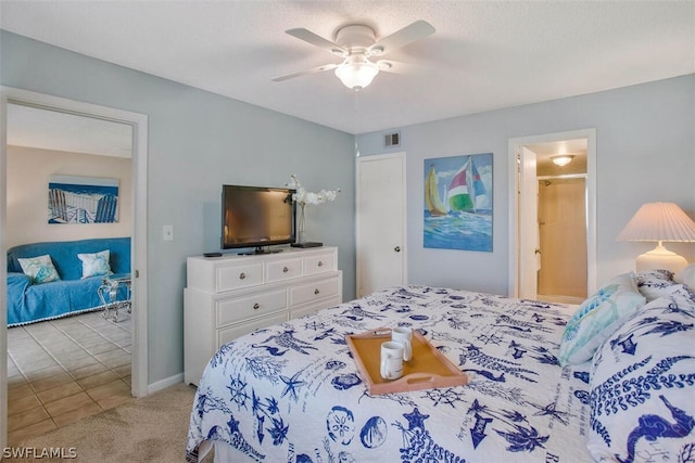 bedroom featuring ensuite bathroom, light colored carpet, and ceiling fan