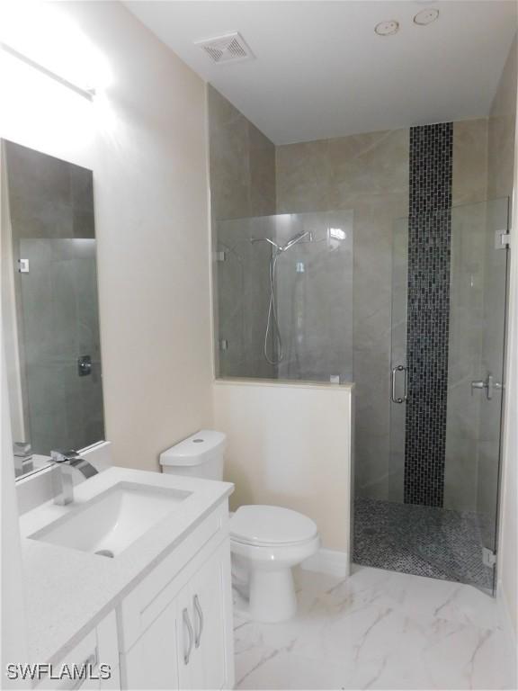 bathroom featuring vanity, toilet, a shower with door, and tile patterned flooring