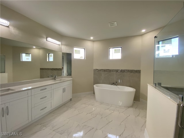 bathroom featuring double vanity, tile walls, tile patterned floors, and a tub